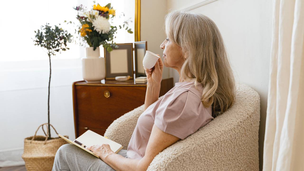 staršia žena sediaca v kresle a pijúca čaj